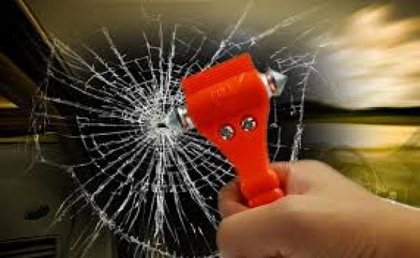 Car safety tool in emergency breaks glass and cuts seat belt if trapped. Shown breaking glass.